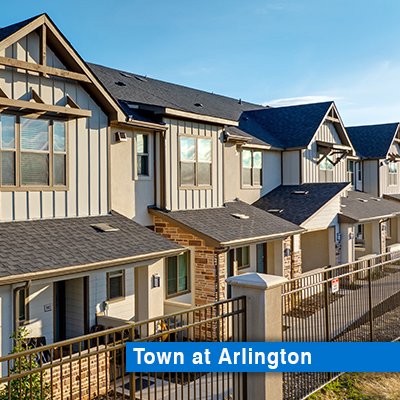 Row of luxury townhomes facing a fence and grass.